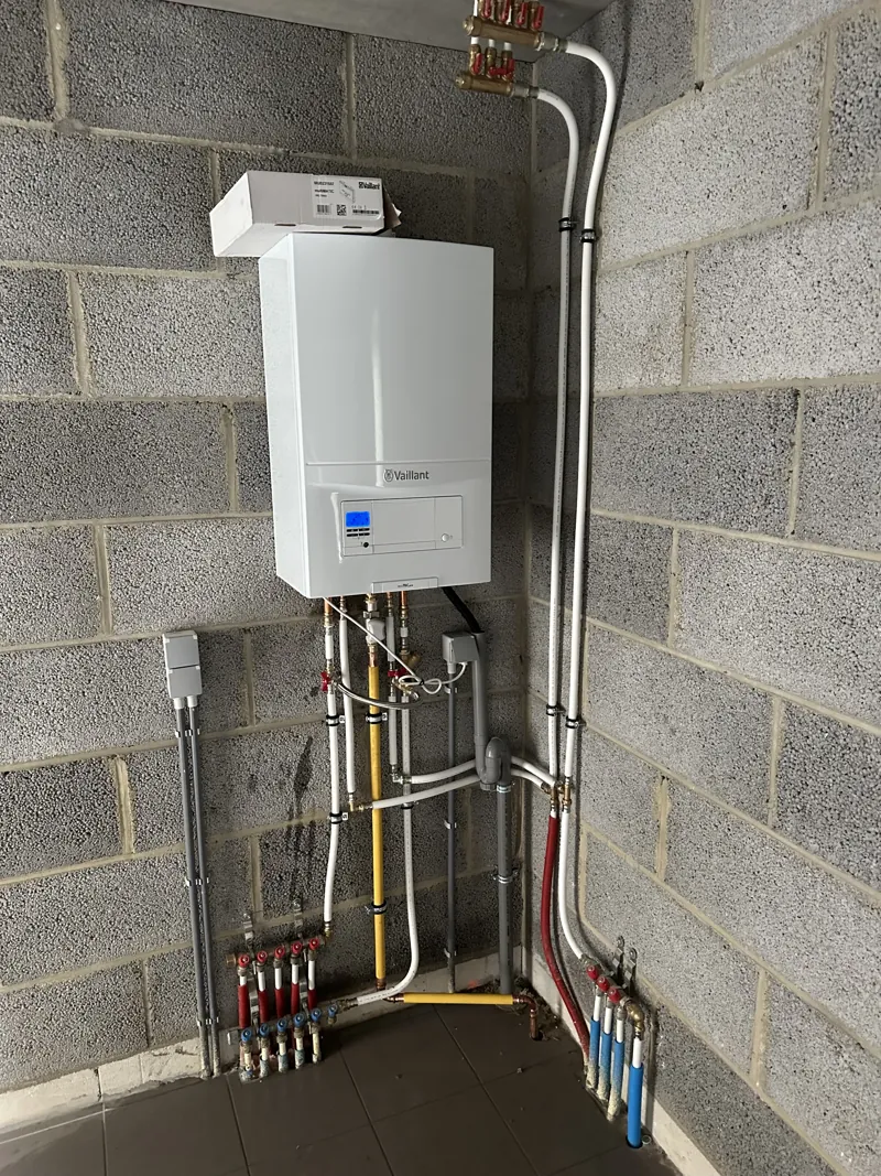 Chaudière gaz murale Vaillant posée sur un mur en blocs avec nourrices PEX, cave neuve