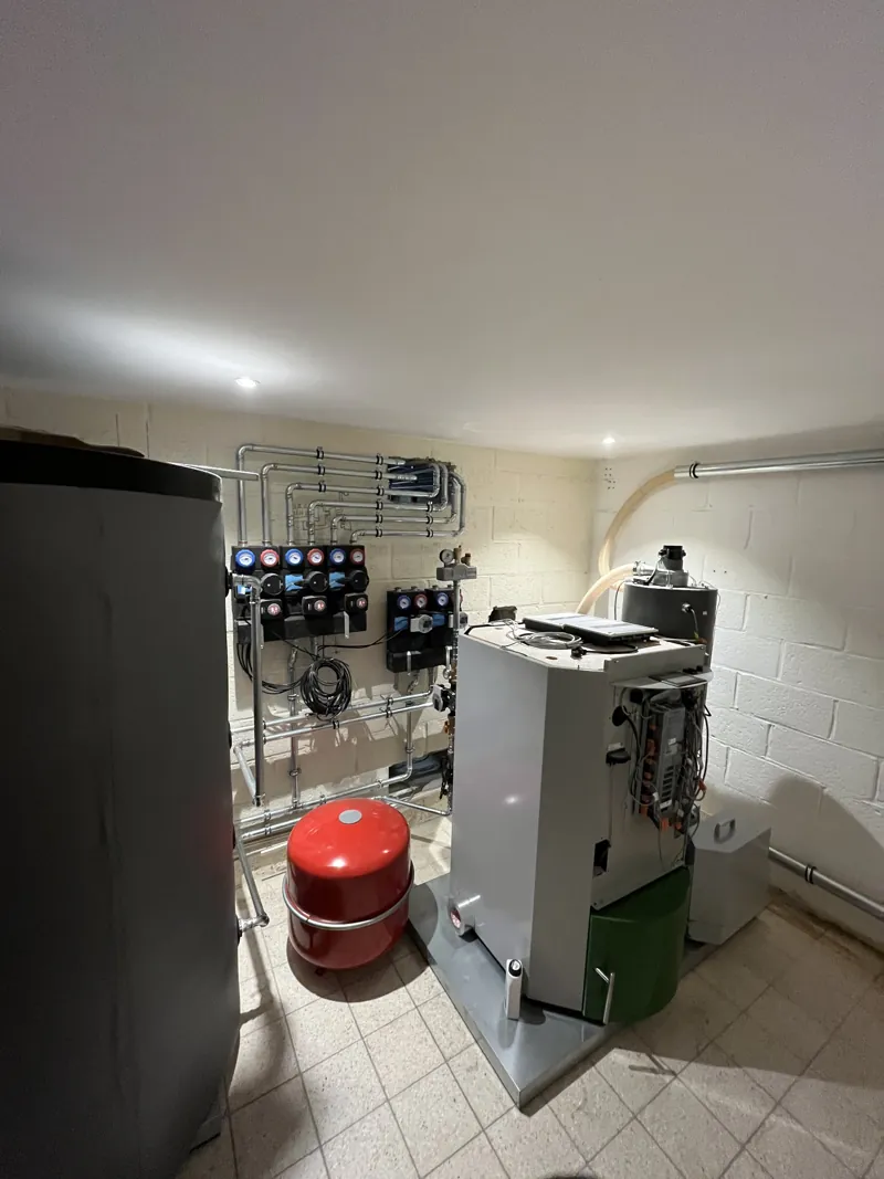 Chaufferie à pellets ÖkoFEN : chaudière, silo, collecteurs avec trois groupes de pompes isolés, groupe d'eau chaude sanitaire, ballon tampon et vase d'expansion