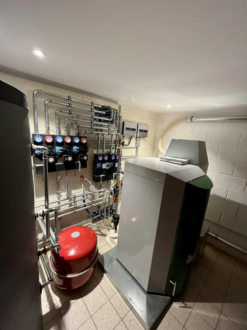 Chaufferie à pellets ÖkoFEN avec chaudière, groupes de pompes isolés, ballon tampon et vase d'expansion dans une cave carrelée