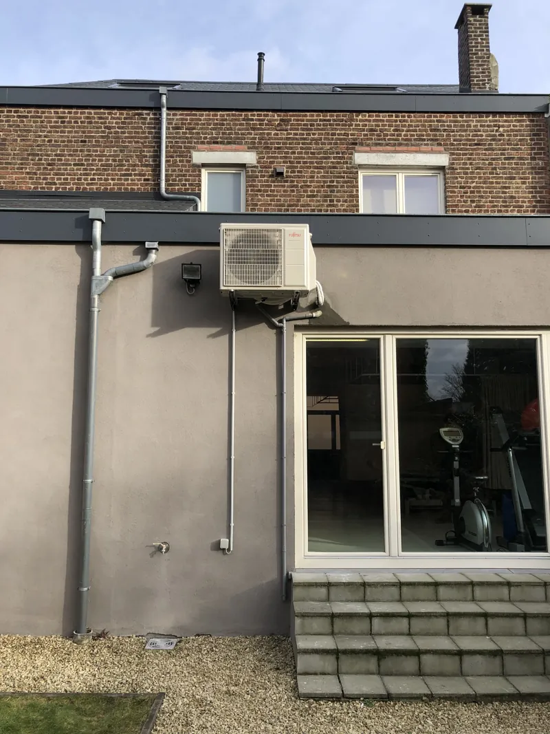 Unité extérieure de climatisation posée sur une façade arrière grise