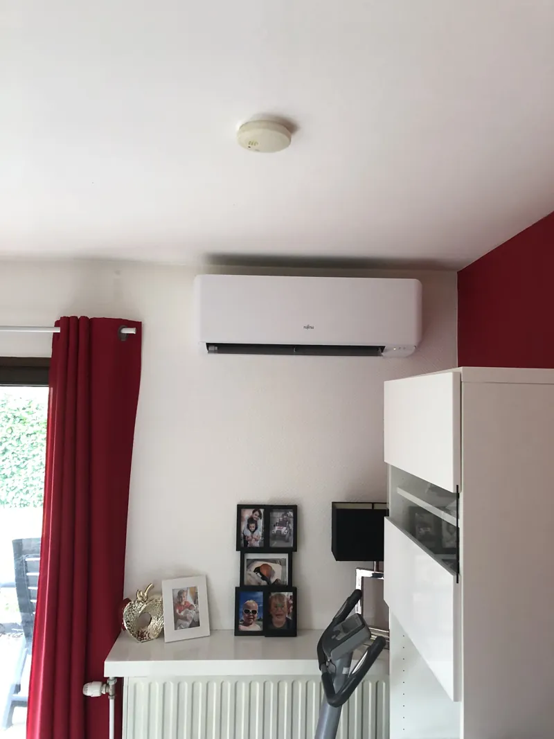 Unité intérieure de climatisation murale dans une chambre au mur rouge
