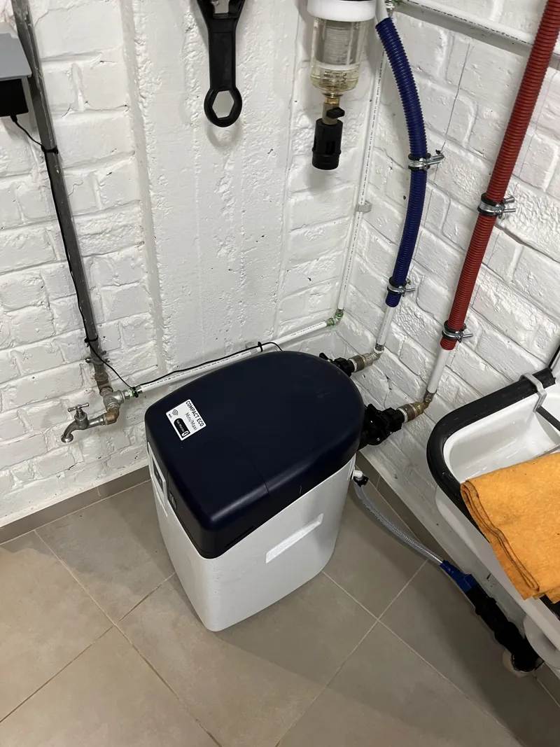 Adoucisseur d'eau et tuyauteries sanitaires rouge et bleu dans un local blanc