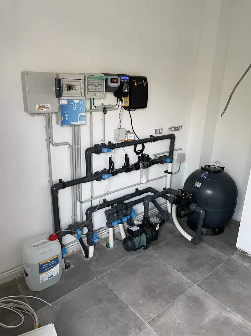 Local technique de piscine carrelé en gris : filtre, pompe, armoire électrique et régulation