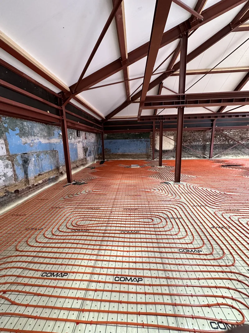 Boucles rouges d'un grand plancher chauffant dans un hall à charpente métallique