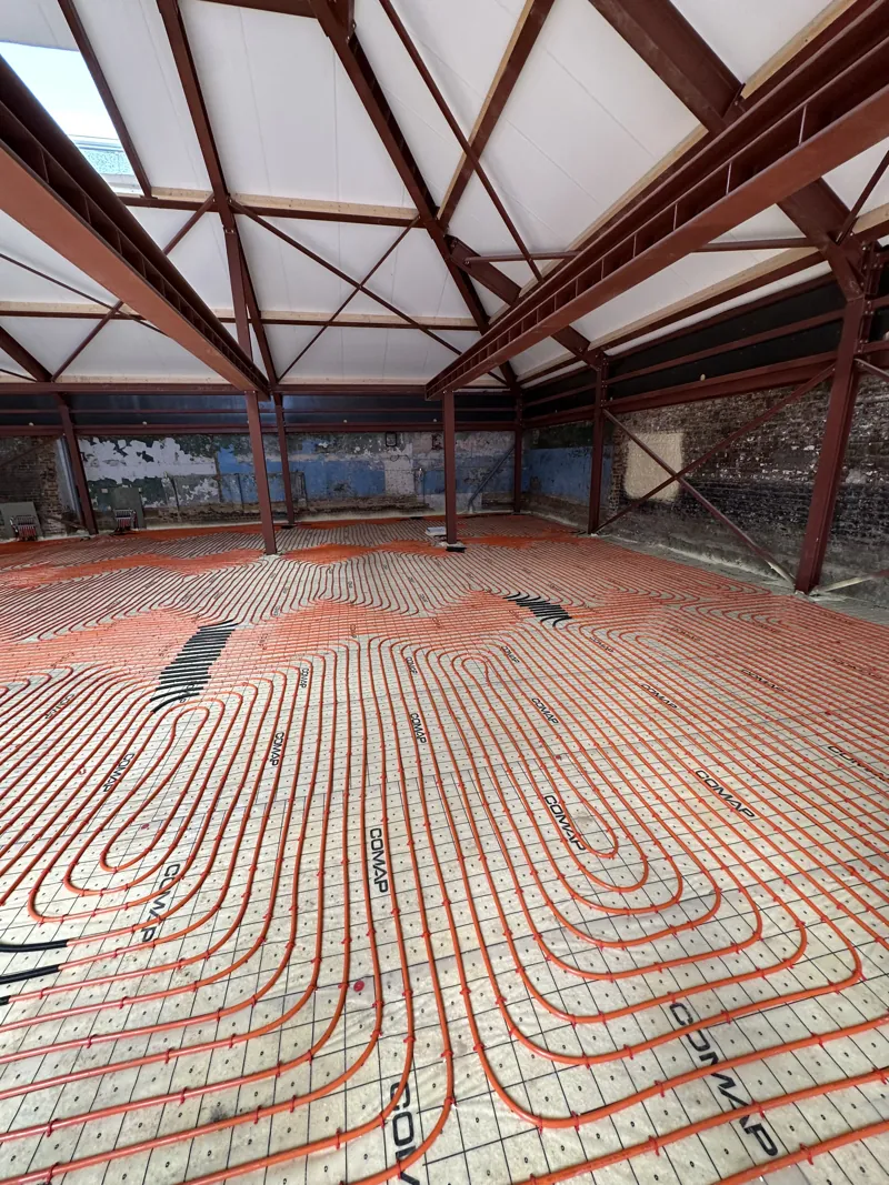 Vue d'ensemble des boucles d'un grand plancher chauffant dans un hall à charpente métallique