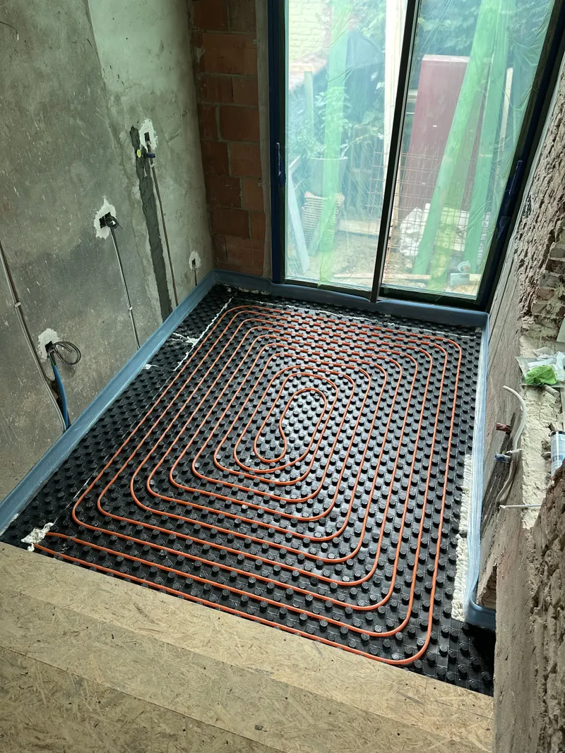 Boucle de plancher chauffant posée dans une salle de bain, sous une baie vitrée